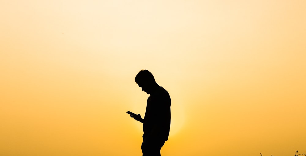 a silhouette of a man using a cell phone