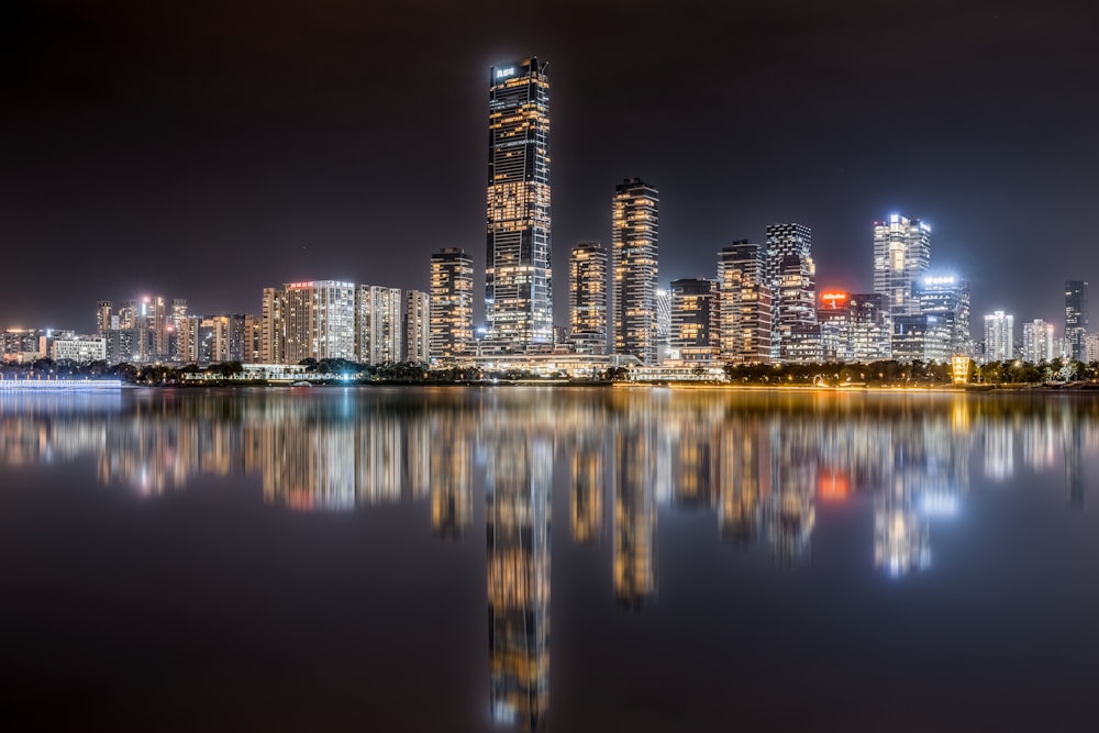 a city skyline at night reflected in a body of water