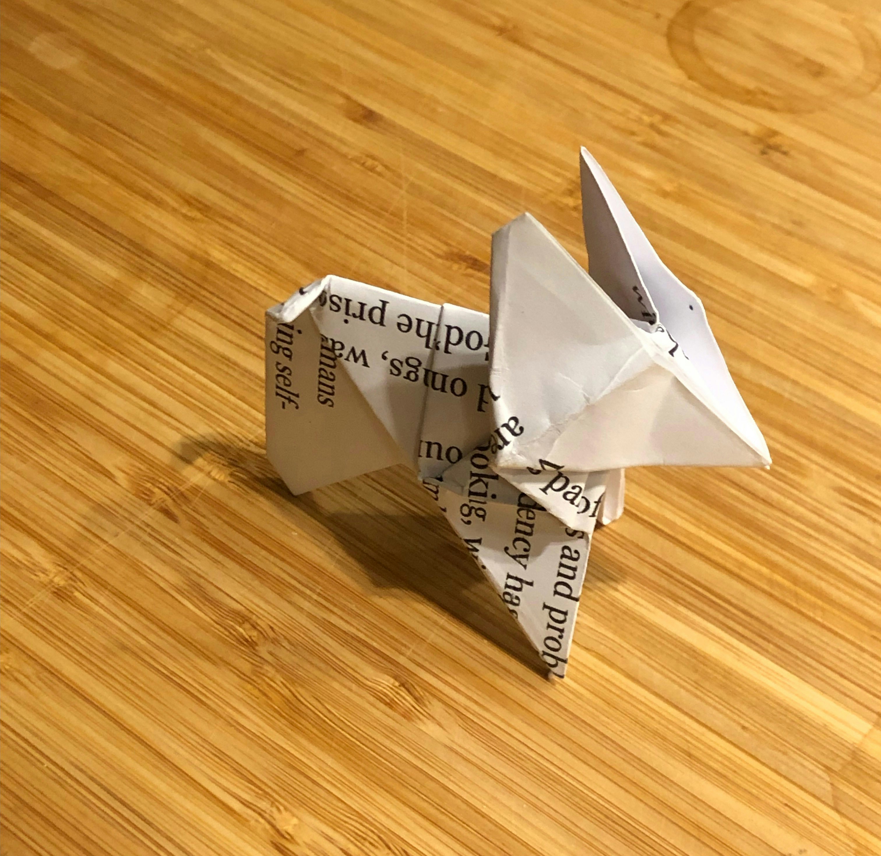 a white origami bird sitting on top of a wooden table