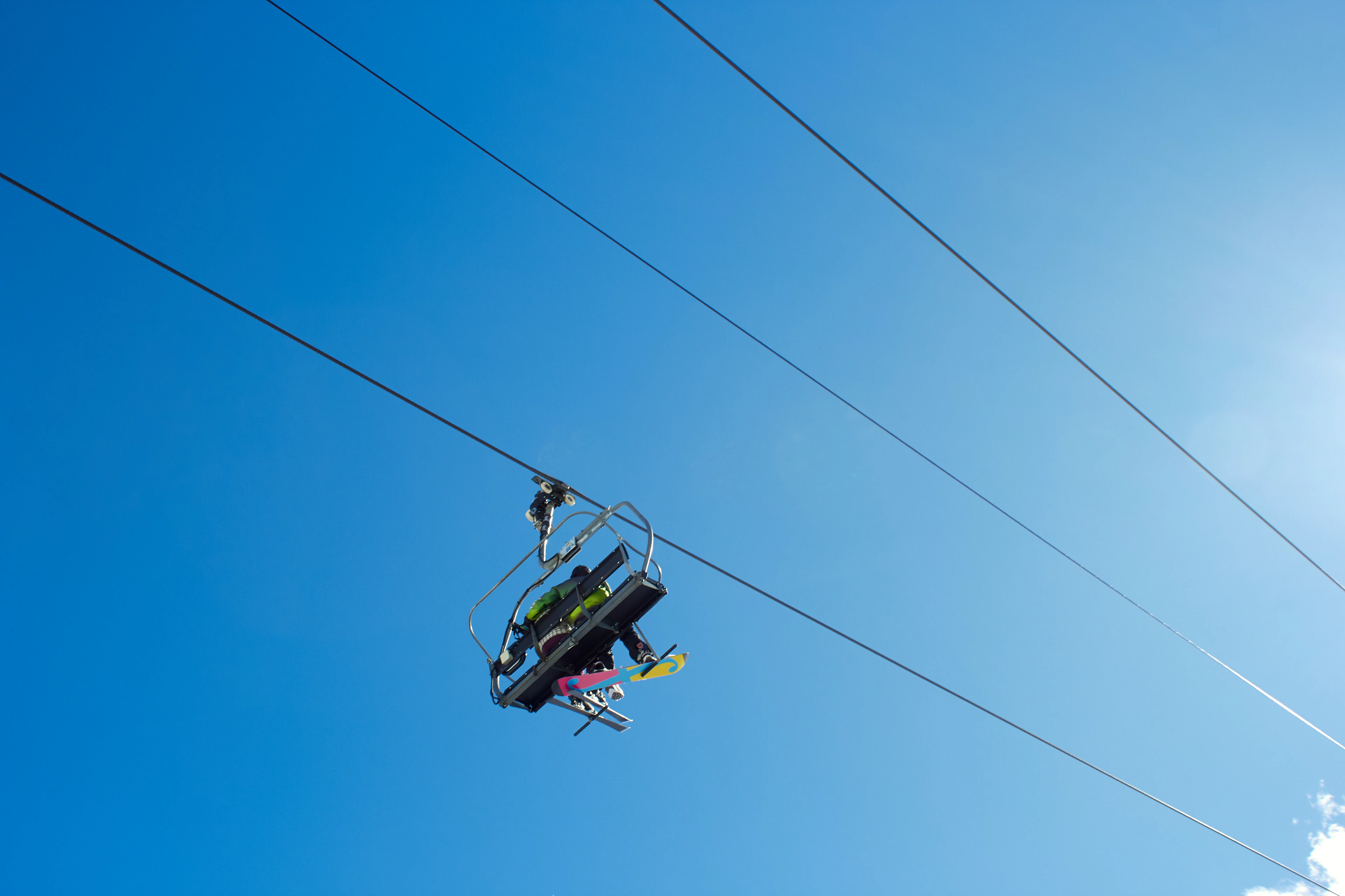 A skier riding a chairlift on a sunny day in Ordino