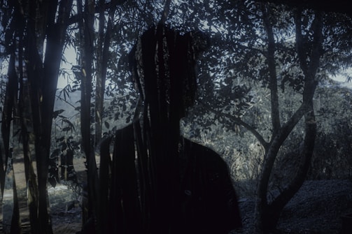 Shadowy silhouette of a tikbalang lurking near twisted trees.