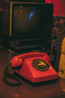 Close-up of a vintage rotary phone and seaside postcards on a bright retro wooden table.