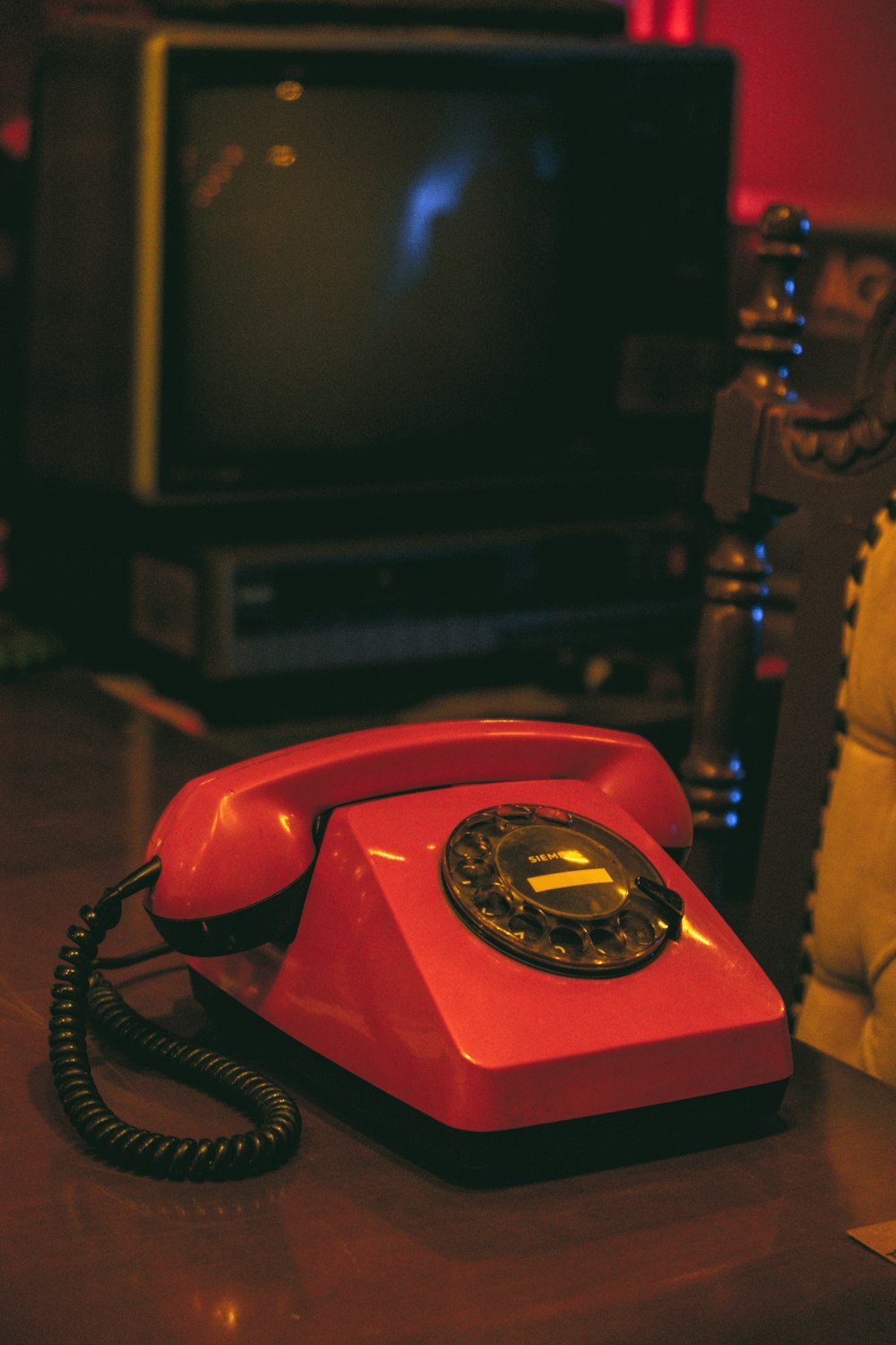 a red phone sitting on a table in front of a tv