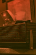 A vintage Grundig radio with a wood and metal design, featuring horizontal grooves on the front panel. The background is slightly blurred, giving a warm, nostalgic atmosphere.