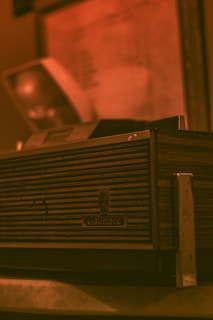 A vintage Grundig radio with a wood and metal design, featuring horizontal grooves on the front panel. The background is slightly blurred, giving a warm, nostalgic atmosphere.