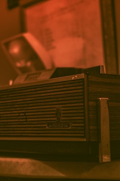 A vintage Grundig radio with a wood and metal design, featuring horizontal grooves on the front panel. The background is slightly blurred, giving a warm, nostalgic atmosphere.