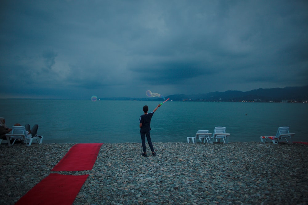 a man flying a kite on the beach at night