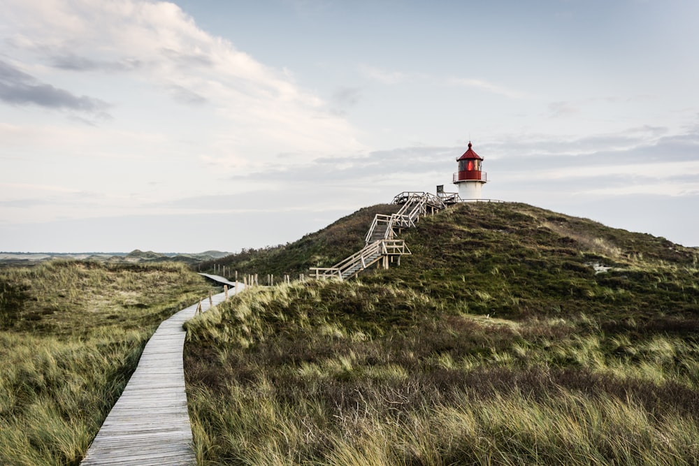 a wooden path leading to a lighthouse on a hill