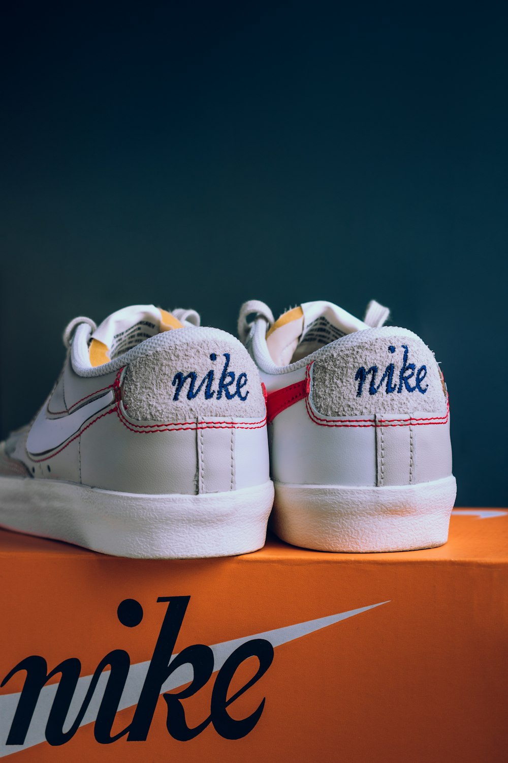 a pair of white nike shoes sitting on top of a box