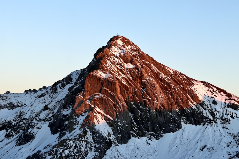 a large mountain covered in snow under a blue sky