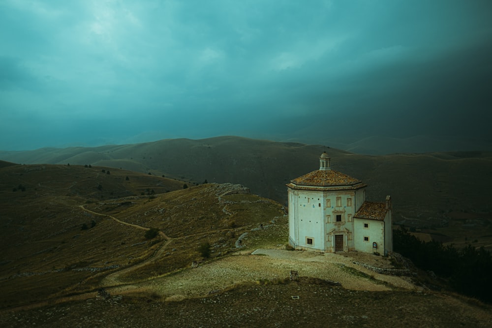 a white building sitting on top of a hill under a cloudy sky