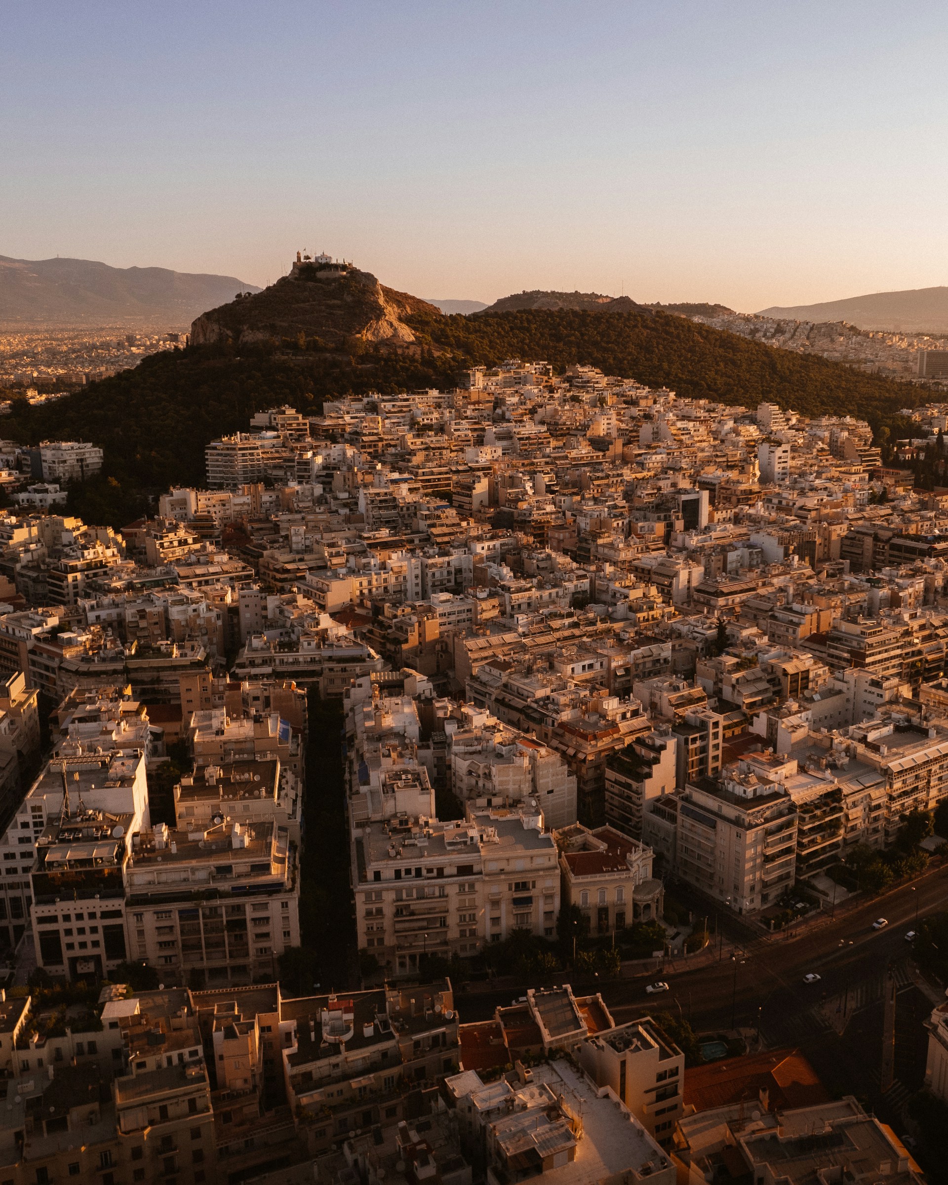 an aerial view of a city with a hill in the background