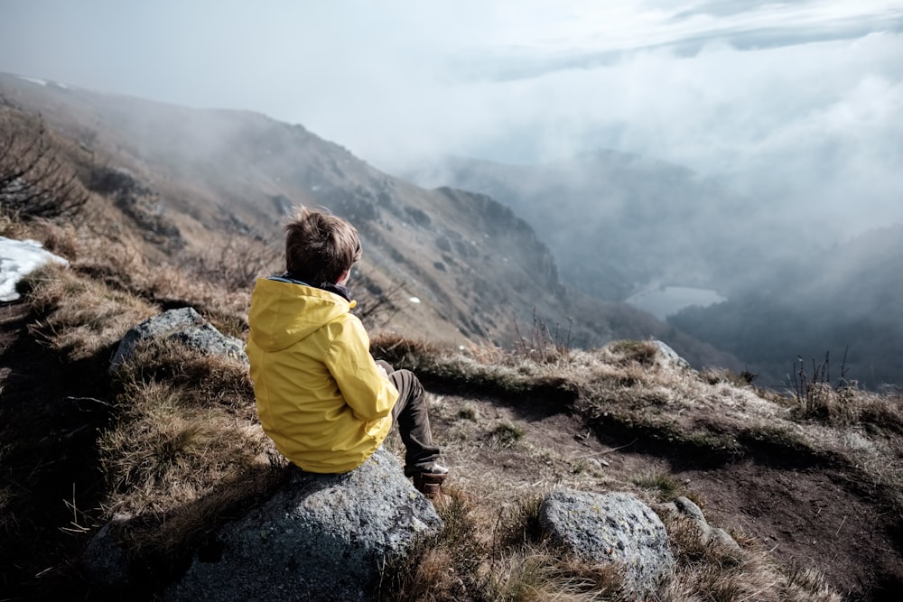 une personne assise au sommet d’une montagne surplombant une vallée