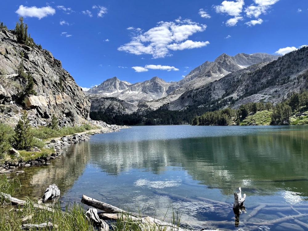 a lake surrounded by mountains under a blue sky