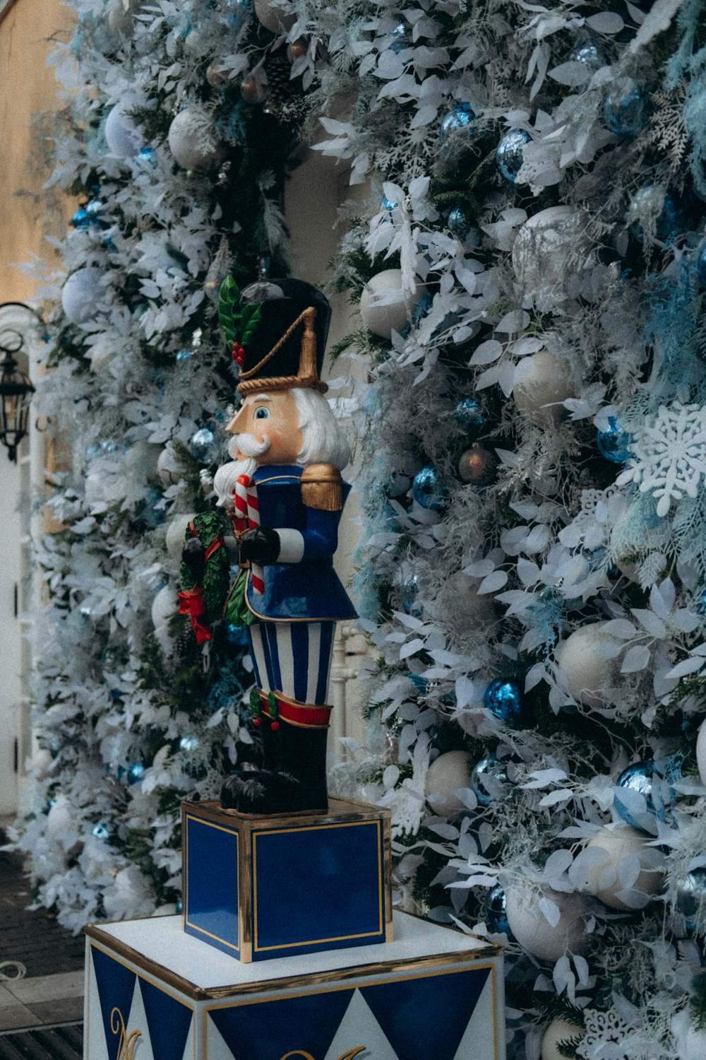 a nutcracker on top of a box in front of a christmas tree