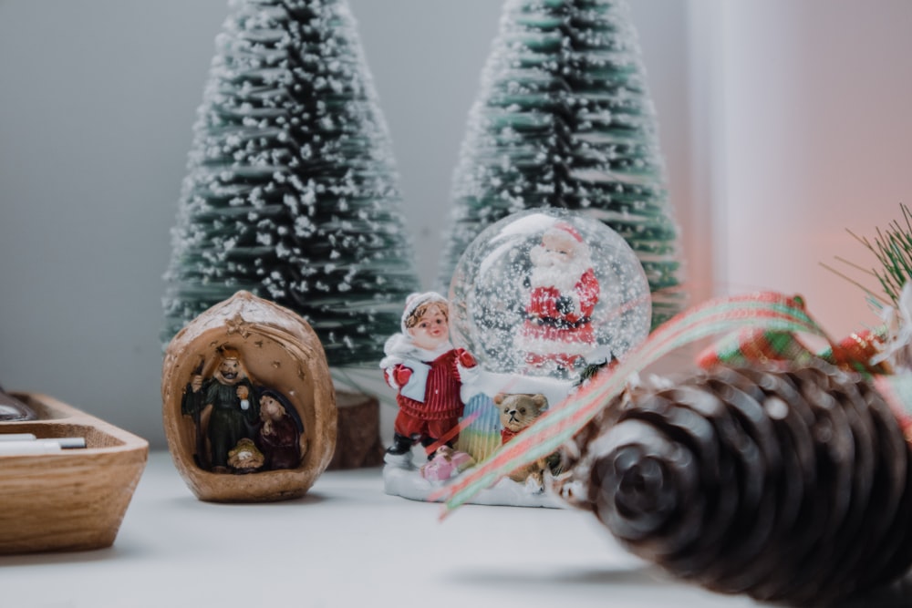 a couple of christmas trees sitting next to a snow globe