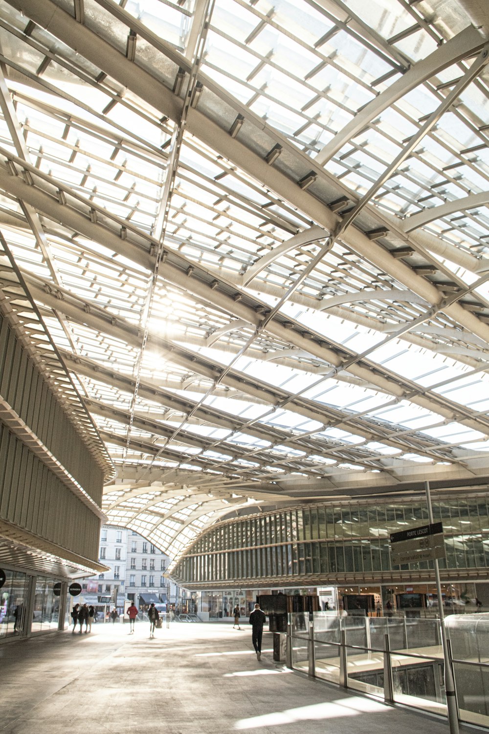 a group of people walking under a glass roof