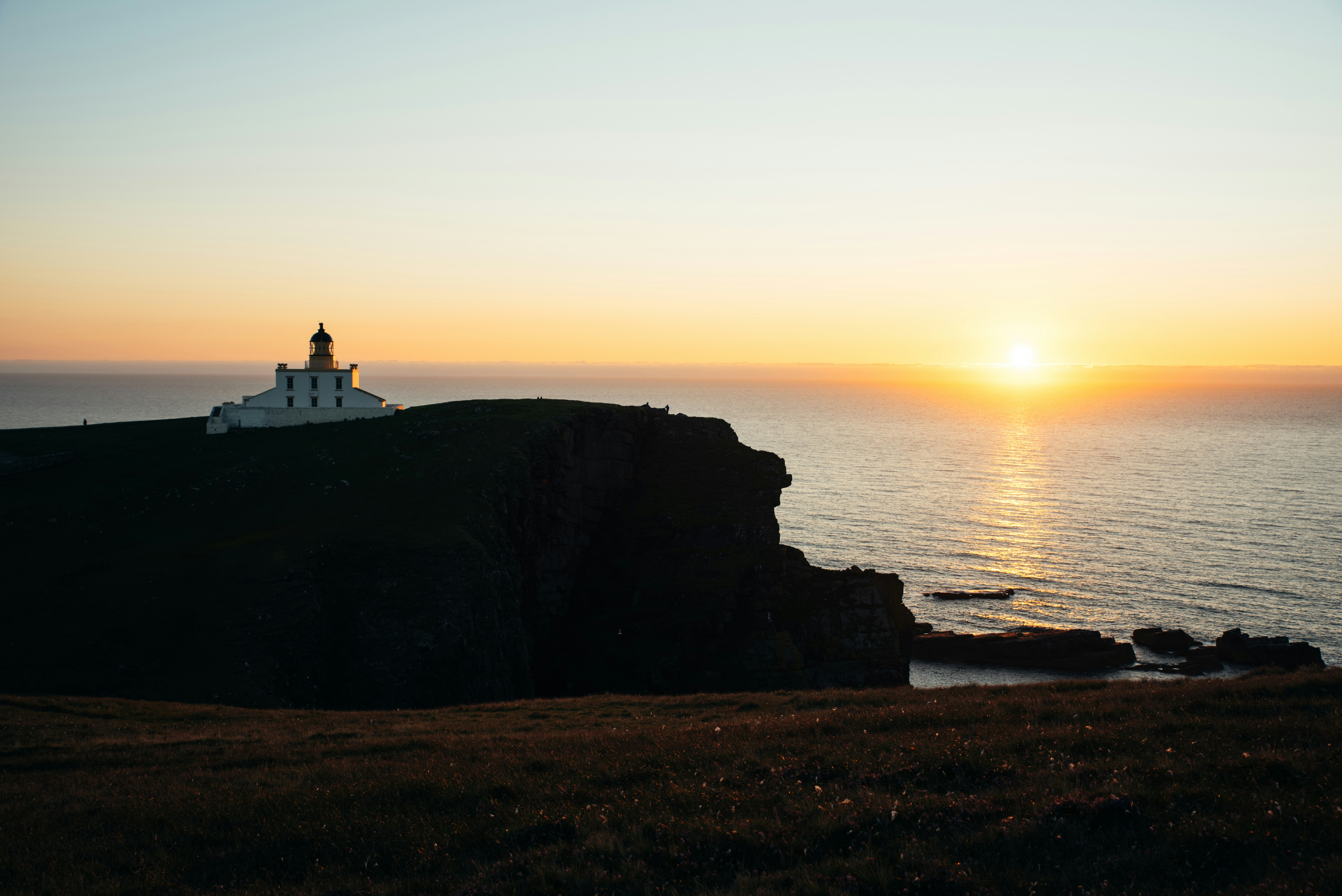 a lighthouse sitting on top of a cliff next to the ocean