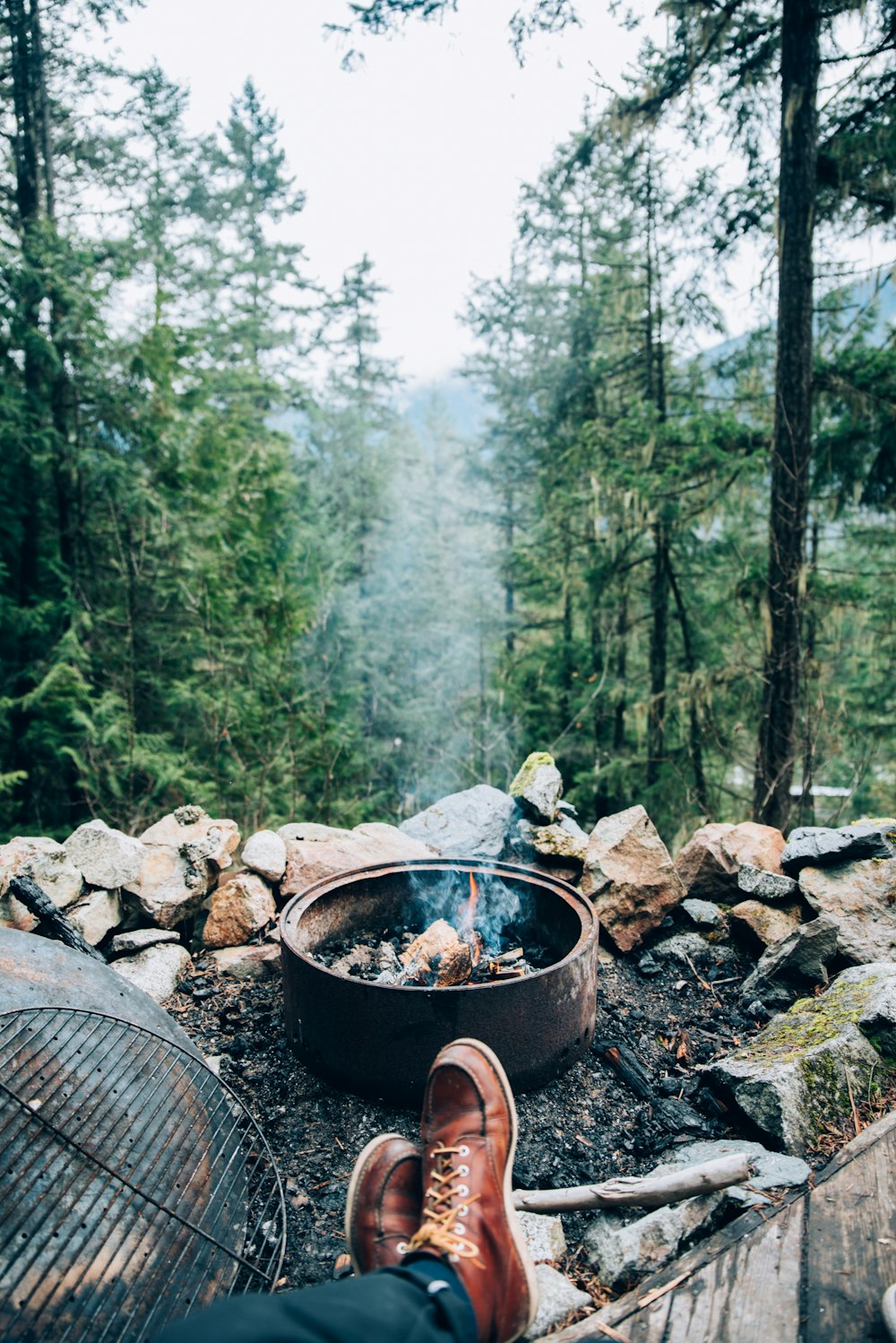 a person sitting in front of a campfire in the woods