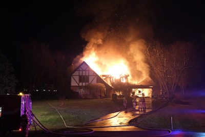 a house on fire at night with a house on fire in the background
