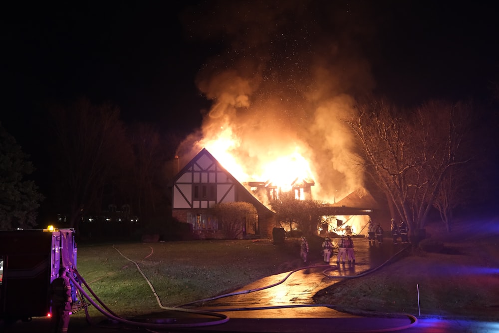 a house on fire at night with a house on fire in the background