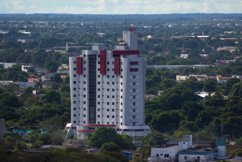 a tall white building with red windows in a city