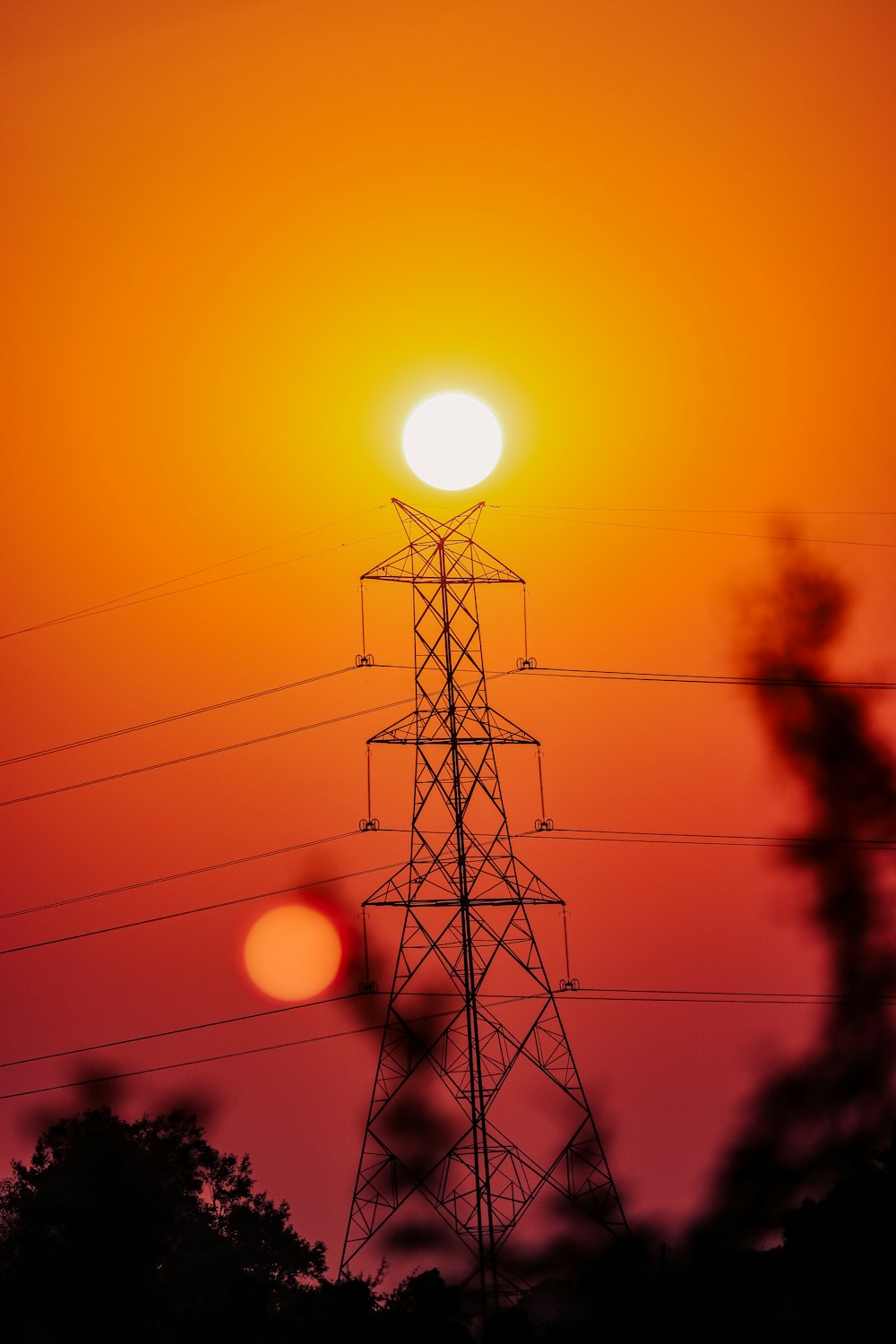 the sun is setting behind an electric tower