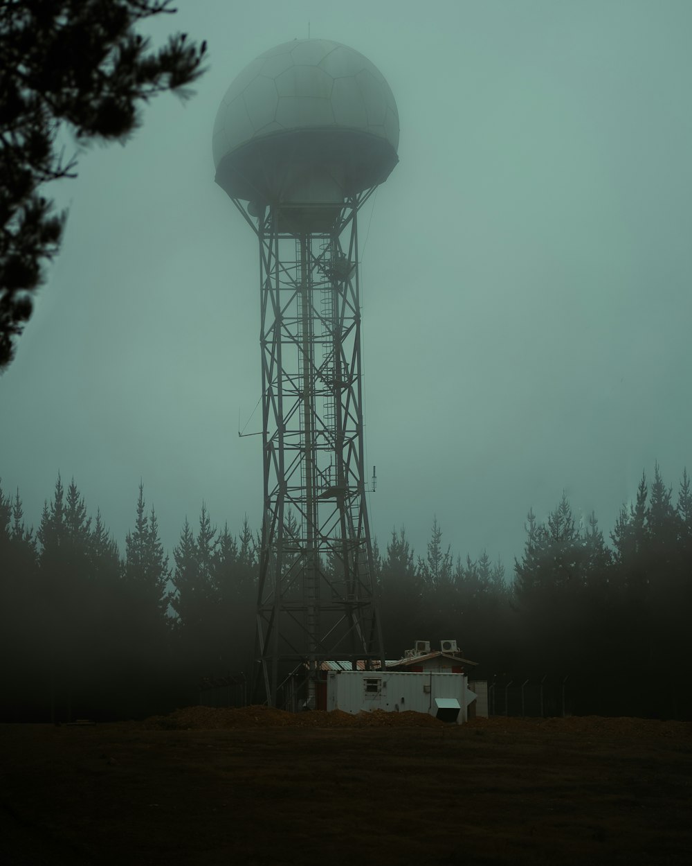 a water tower in the middle of a foggy forest