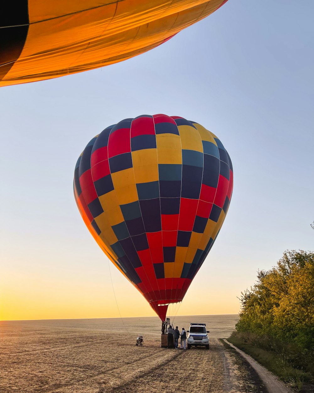 a large hot air balloon flying over a dirt road