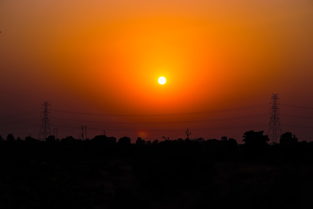 the sun is setting over a field of power lines