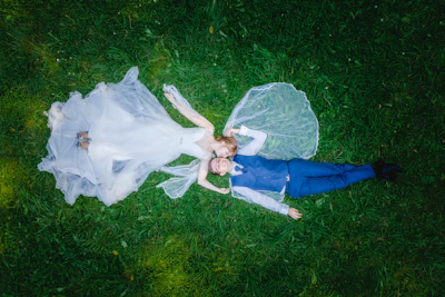 a bride and groom laying on the grass