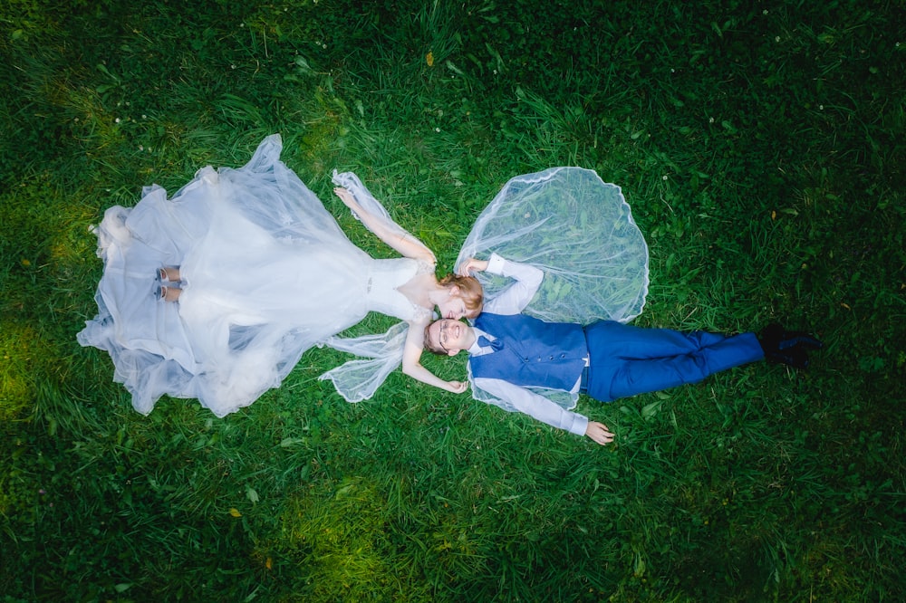 a bride and groom laying on the grass