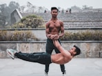 a man doing a handstand on another man