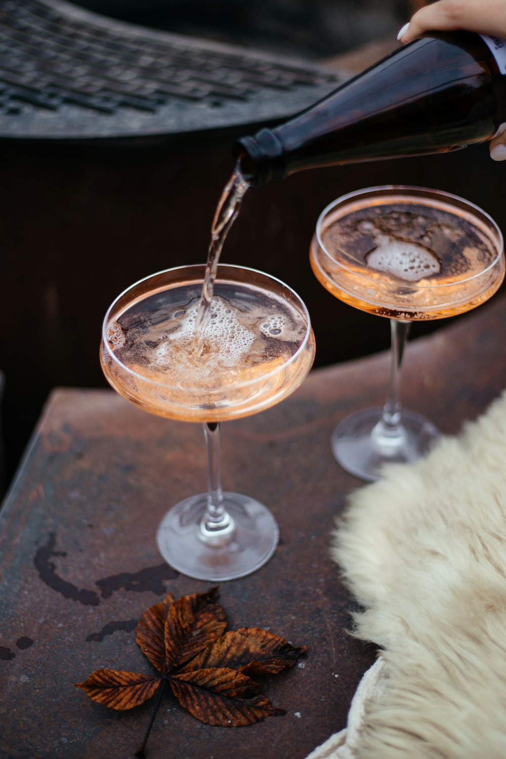 a person pouring a drink into two glasses