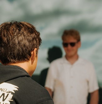 a man standing next to another man in front of a window