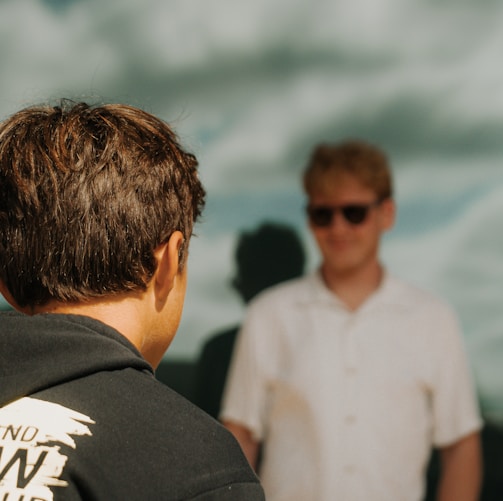 a man standing next to another man in front of a window