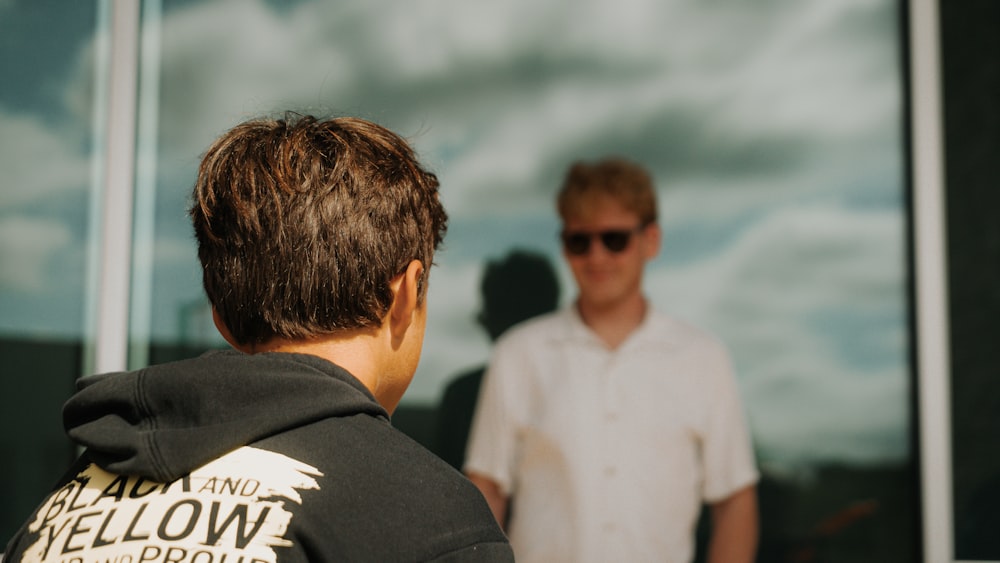 a man standing next to another man in front of a window