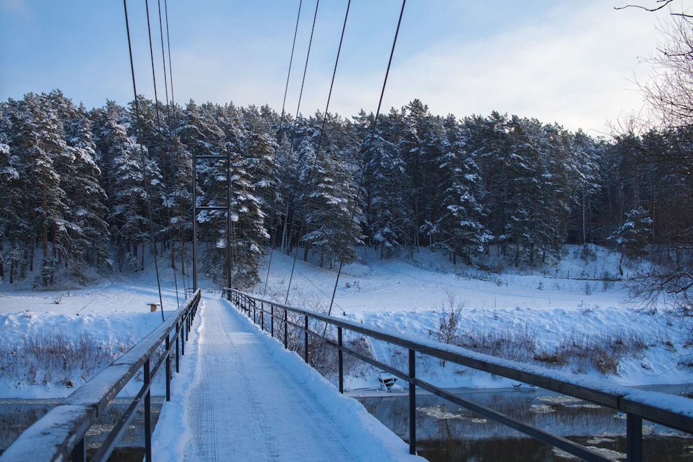 a snow covered bridge over a small stream