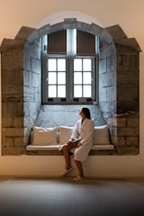 a woman is sitting on a window sill