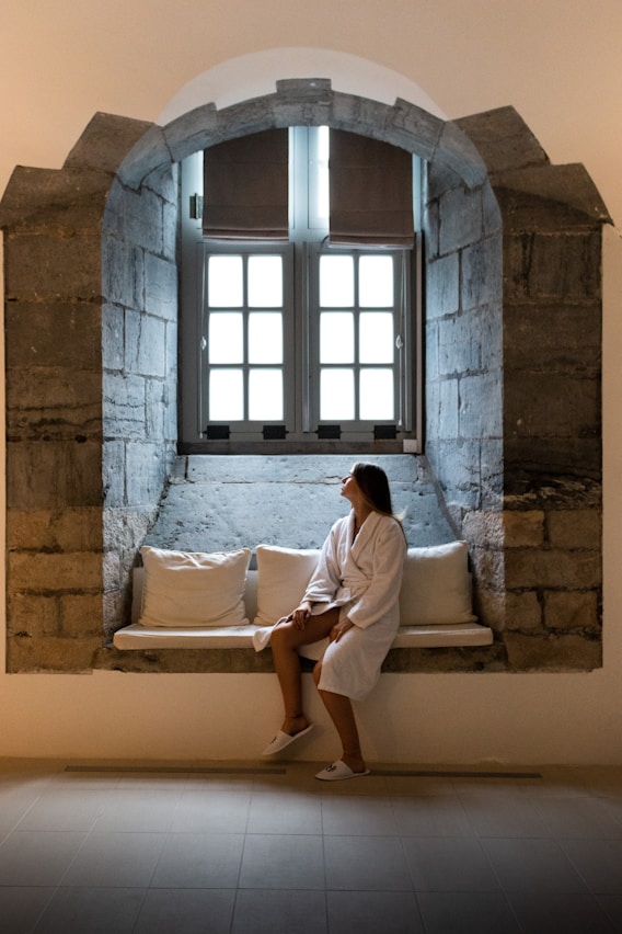 a woman is sitting on a window sill
