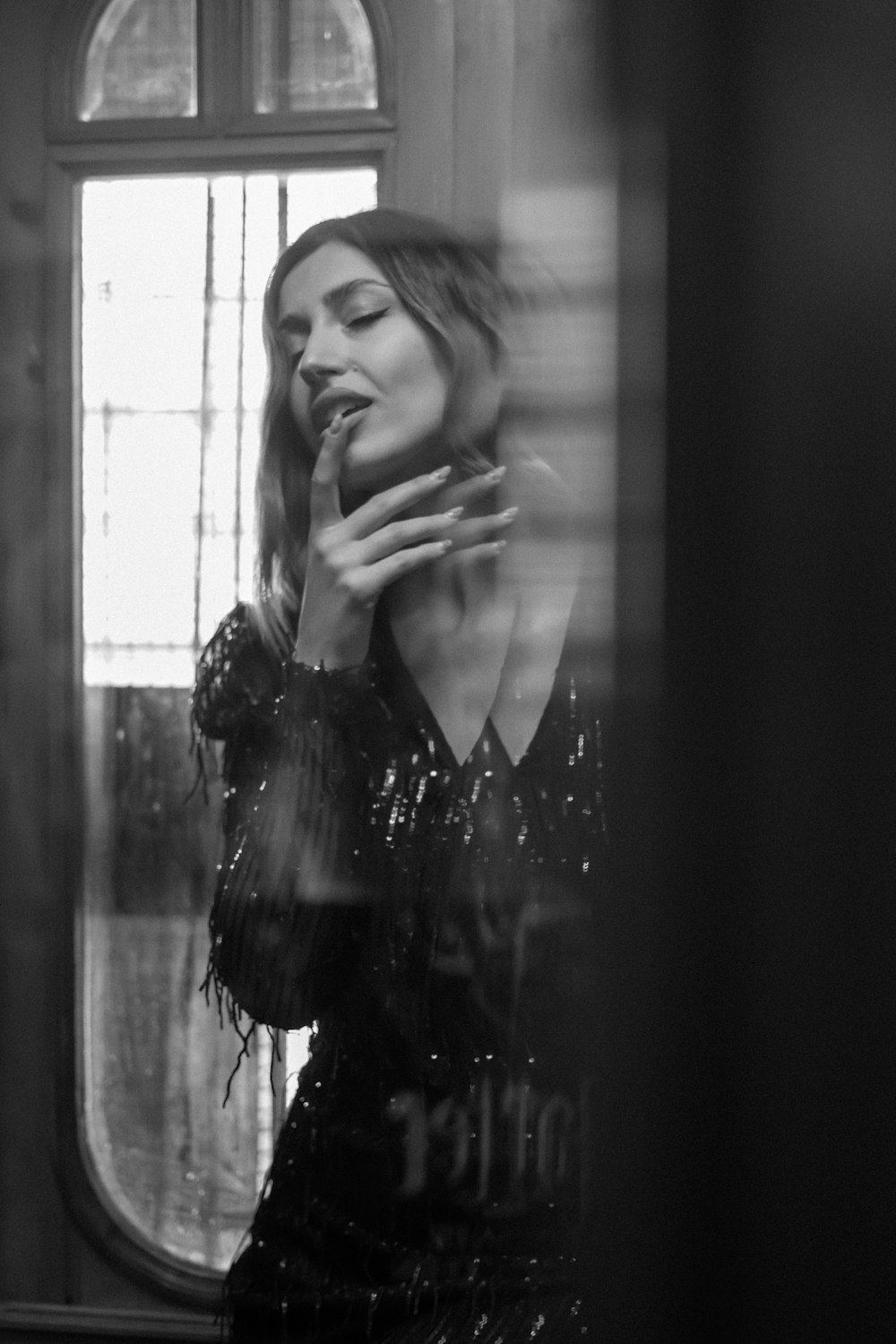 a woman standing in front of a window smoking a cigarette
