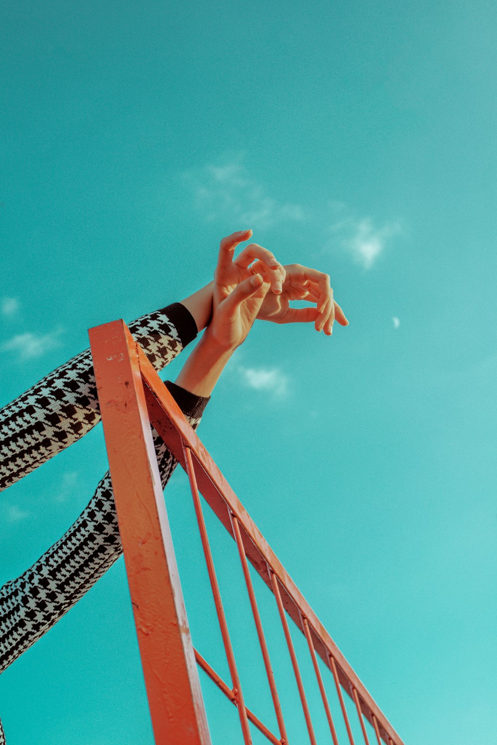 a person reaching up into the air from a metal railing