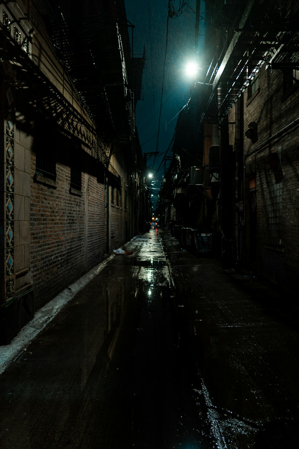 a dark alley way with a street light in the distance