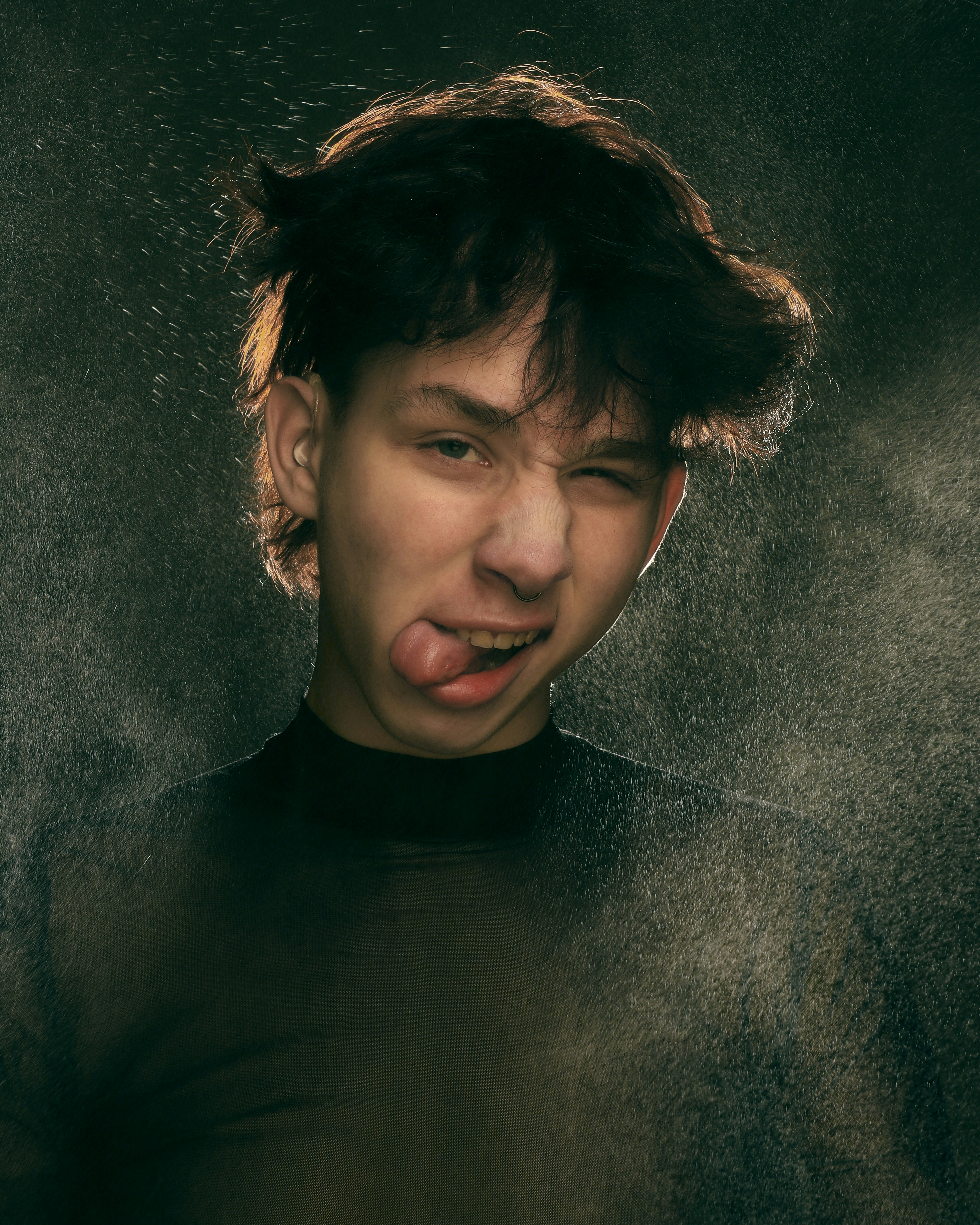 a man sticking his tongue out in front of a black background