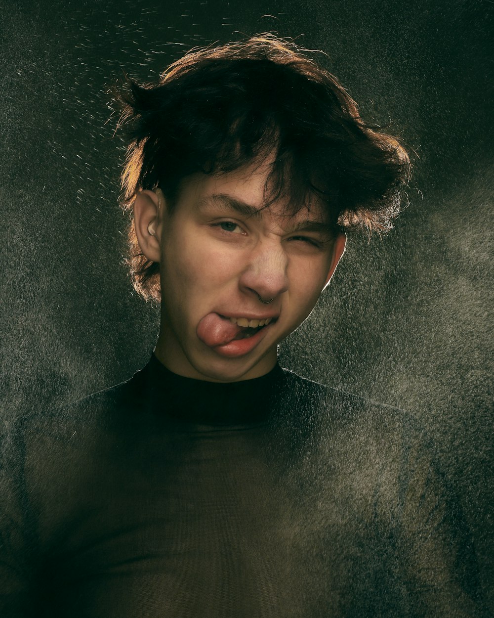 a man sticking his tongue out in front of a black background