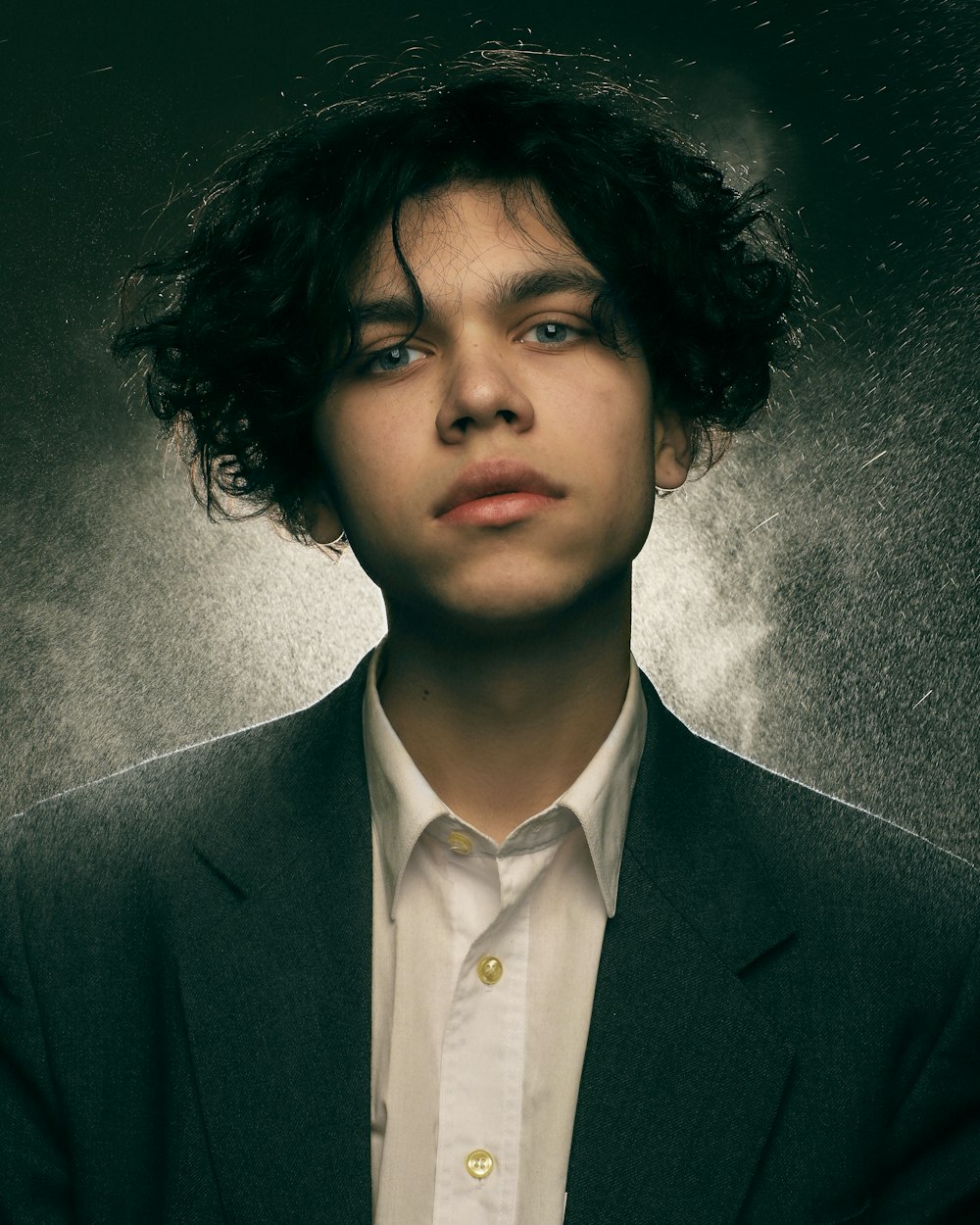 a young man with curly hair wearing a suit