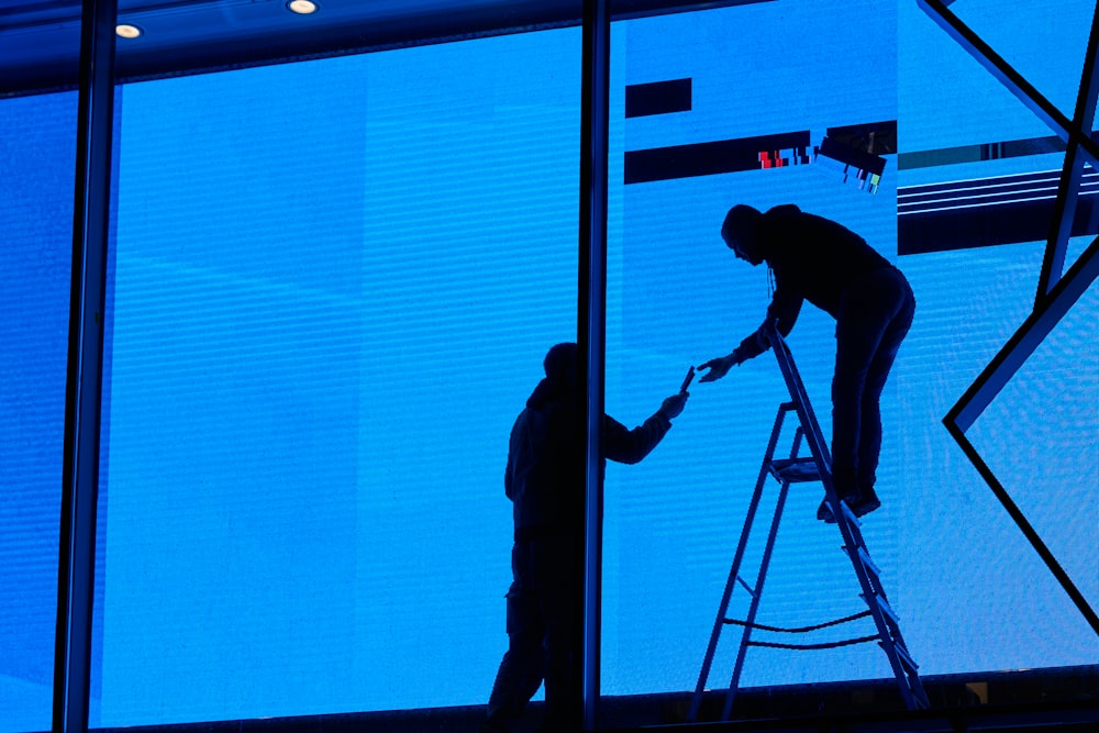 a man standing on a ladder next to a window