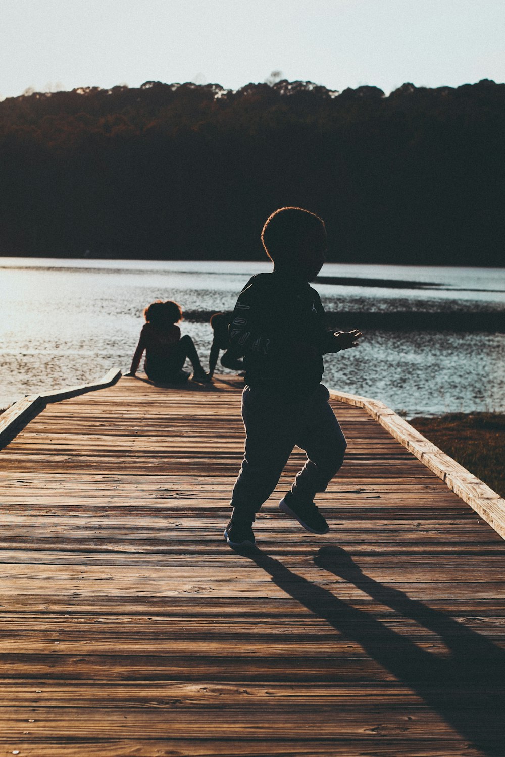 a young boy running across a wooden bridge