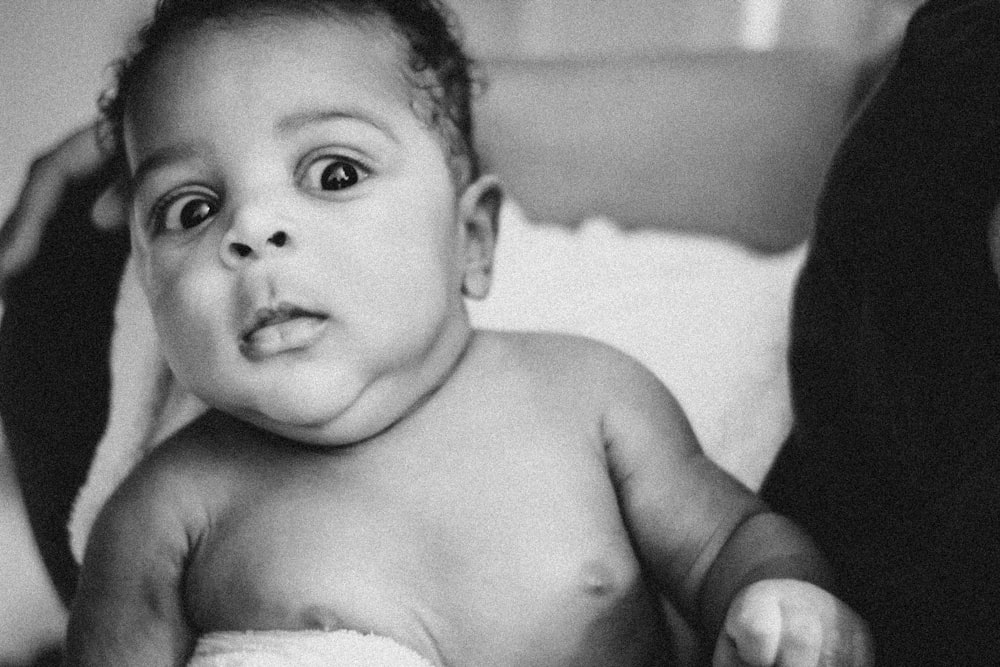 a black and white photo of a baby on a bed