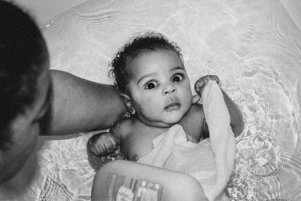 a black and white photo of a baby in a bath tub